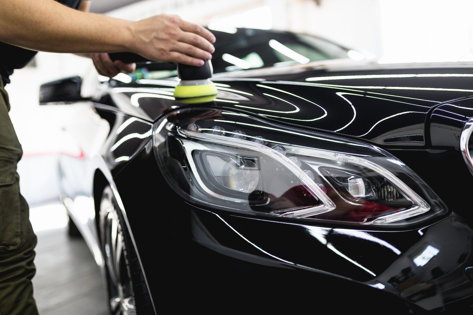 Carro preto com a pintura brilhando sob as luzes do box
